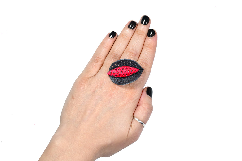 Mano luciendo el anillo artesanal de arcilla polimérica modelo Cala, en color rojo.