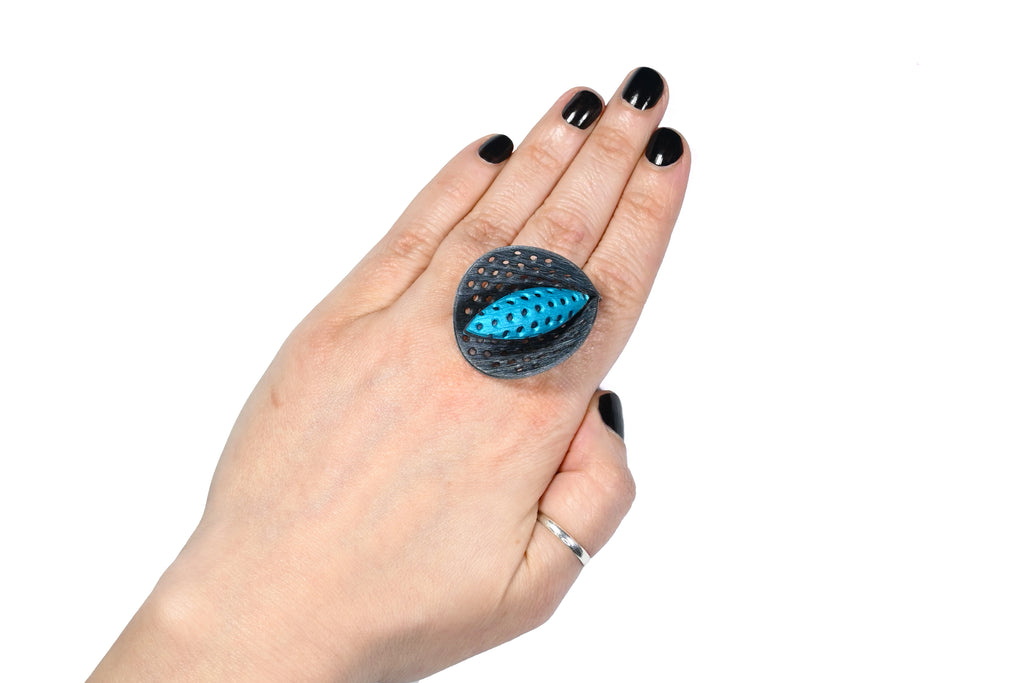 Mano luciendo el anillo artesanal de arcilla polimérica modelo cala, en color turquesa.