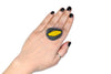 Mano luciendo el anillo artesanal de arcilla polimérica modelo Cala, en color amarillo.