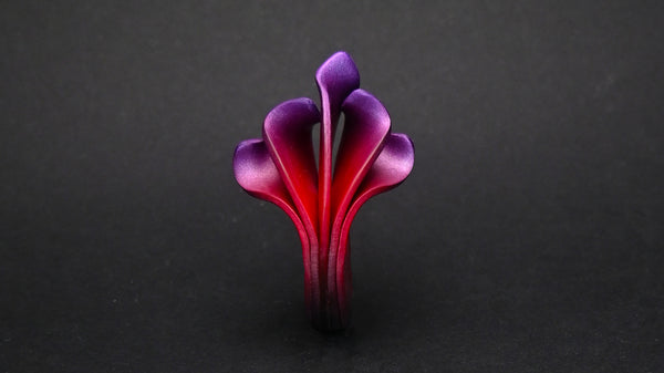 Anillo artesanal de arcilla polimérica con diseño en forma de llamas en colores metálicos, degradados de rojo a violeta.