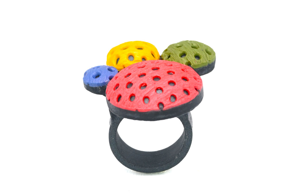 Anillo artesanal de arcilla polimérica con diseño en círculos de distintos tamaños en colores vibrantes.