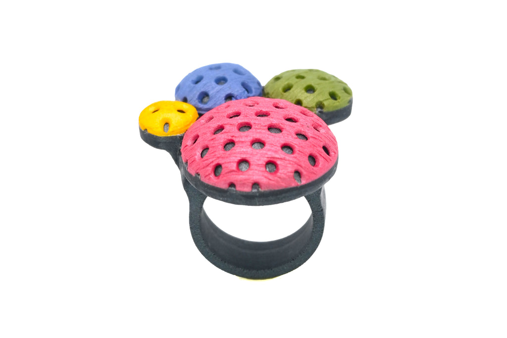 Anillo artesanal de arcilla polimérica con diseño en círculos de distintos tamaños en colores vibrantes.