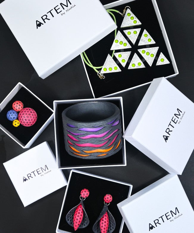 Cajas con el logotipo de Artem by Nadia y joyas artesanas hechas a mano con arcilla polimérica.