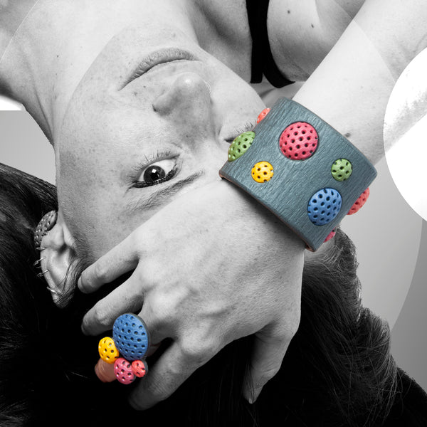 Chica luce el conjunto de anillo y pulsera artesana de arcilla polimérica con diseño Polka Dots en colores vibrantes.