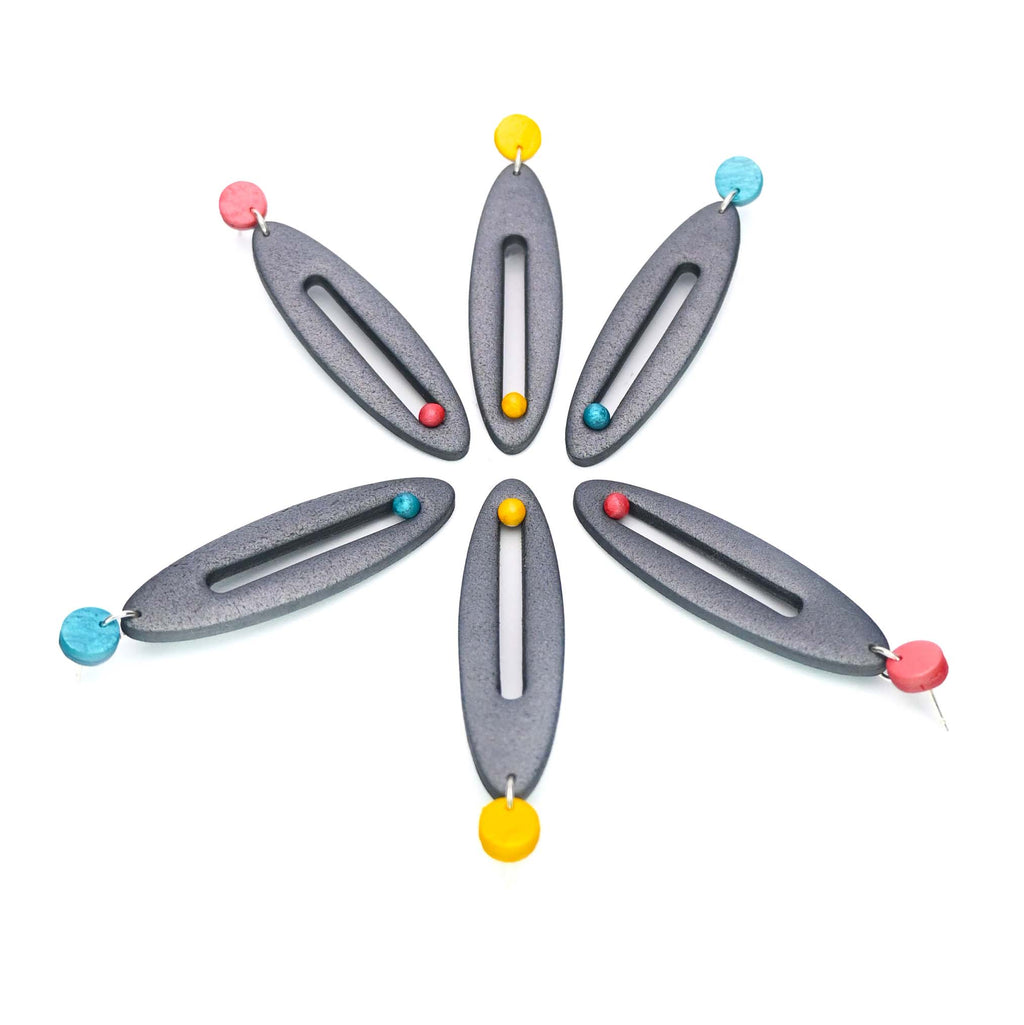 Imagen de los pendientes hechos a mano, modelo Esencia en tres colores sobre fondo blanco, colocados en forma original