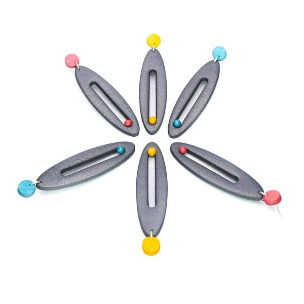 Imagen de los pendientes hechos a mano, modelo Esencia en tres colores sobre fondo blanco, colocados en forma original