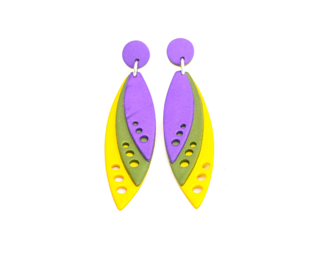 Imagen de los pendientes hechos a mano, modelo Tríada con diseño de capas en color púrpura, verde y amarillo sobre fondo blanco