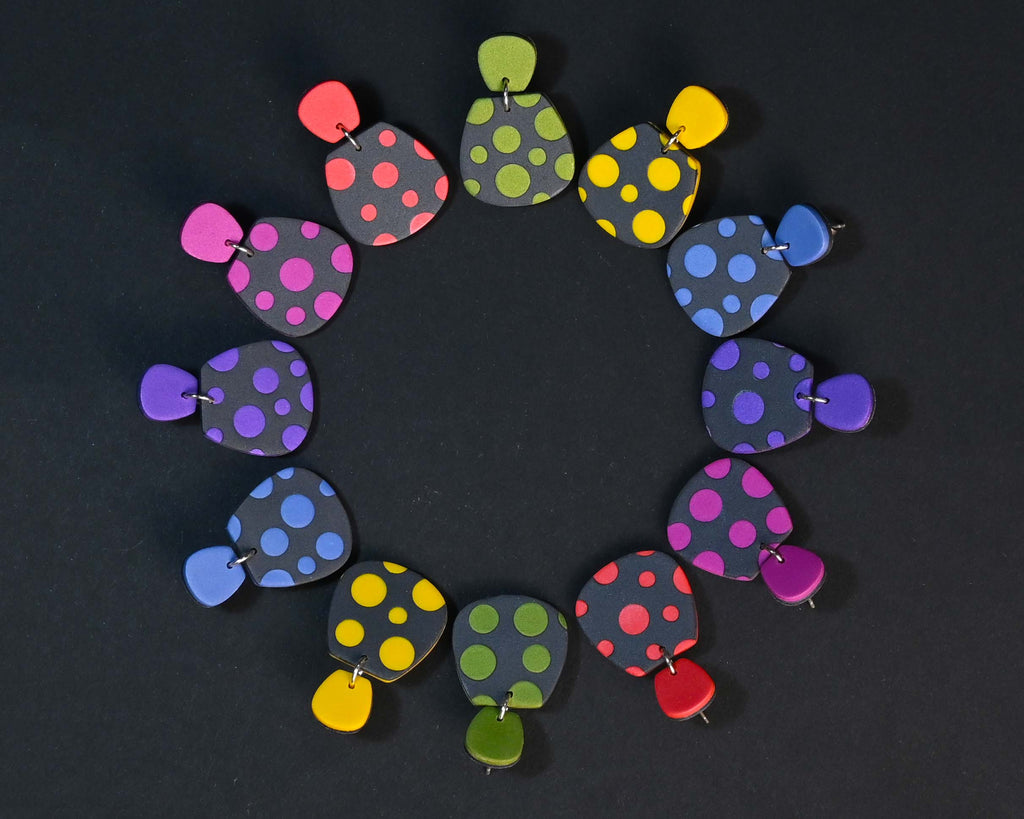Imagen de los pendientes hechos a mano, modelo Verbena con diseño de de lunares en gama de colores sobre fondo negro, dispuestos en forma circular