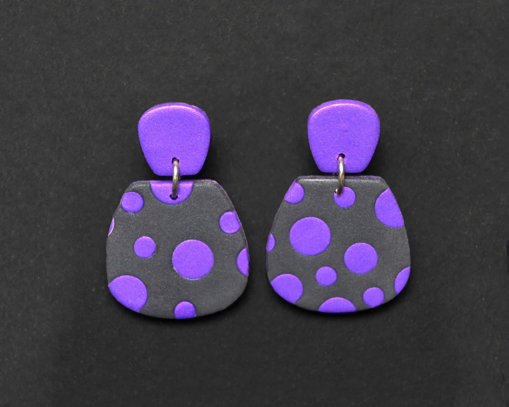 Imagen de los pendientes hechos a mano, modelo Verbena con diseño de de lunares púrpura sobre fondo negro