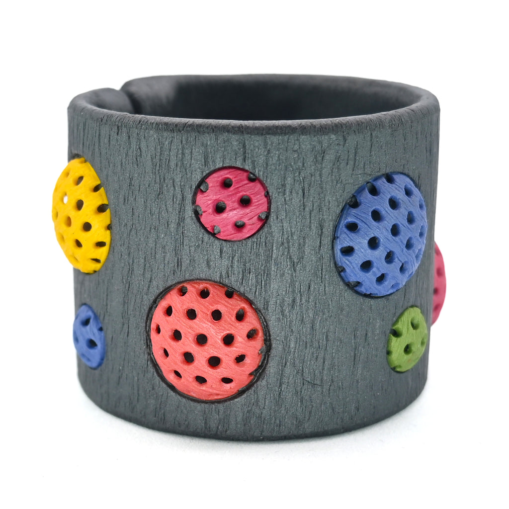 Pulsera artesanal de arcilla polimérica con diseño en círculos de distintos tamaños en colores vibrantes.