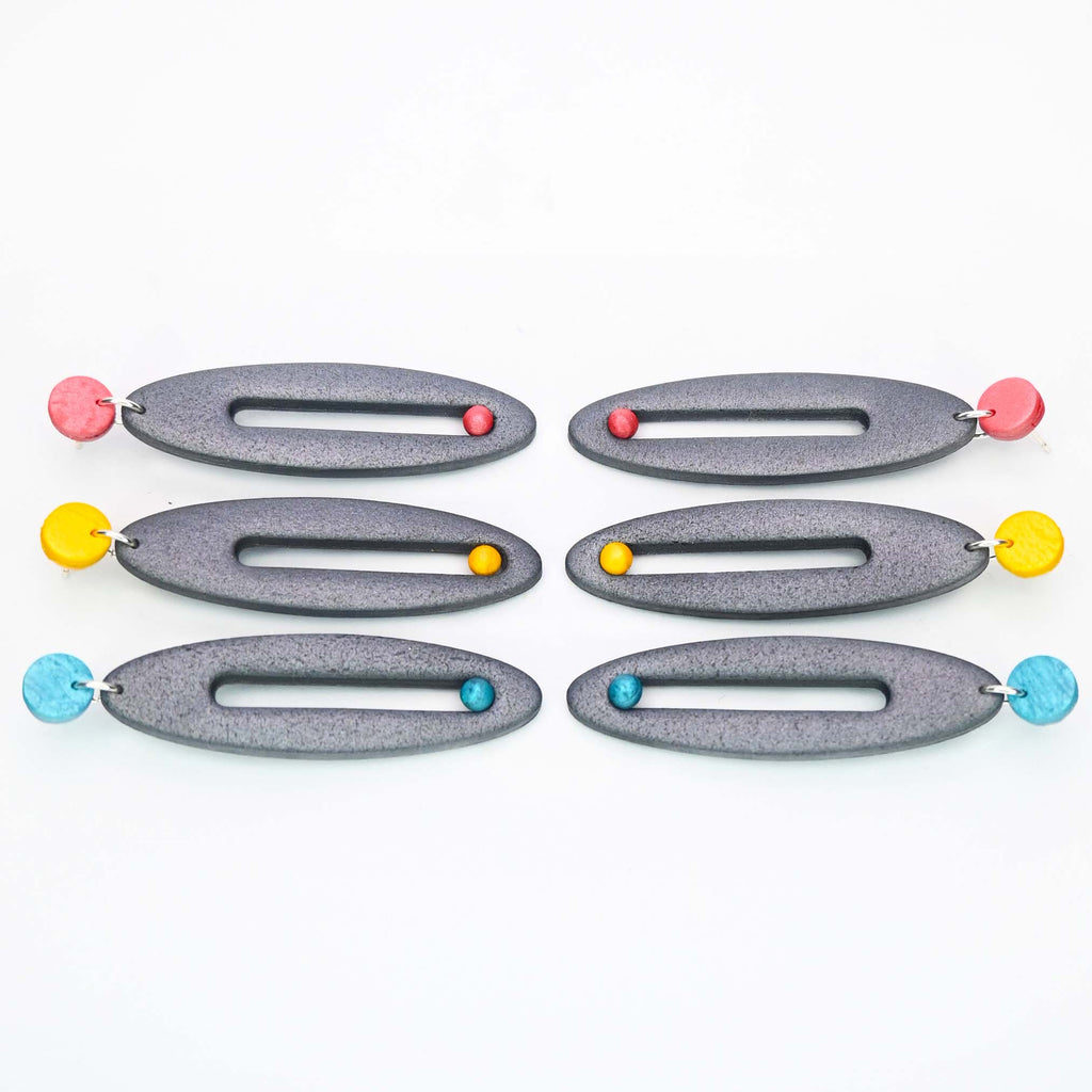 Imagen de los pendientes hechos a mano, modelo Esencia en tres colores sobre fondo blanco, colocados en forma rectangular 