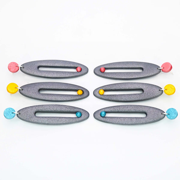 Imagen de los pendientes hechos a mano, modelo Esencia en tres colores sobre fondo blanco, colocados en forma rectangular 